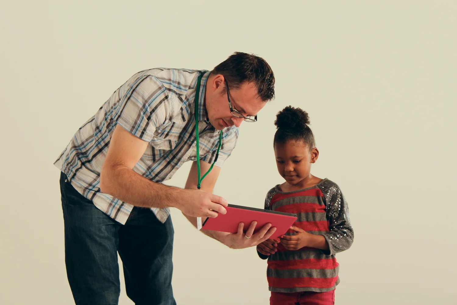 Dan Roesch reviewing an iPad with a young girl on a white studio set